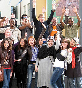 图片来源：Ausschnitt einer Gruppe International Studierende，die die Hände in Luft reißen und sich freuen。