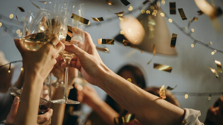 用香槟酒杯举杯祝酒，五彩纸屑在空中飞舞。 