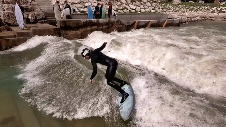 Ein Surfer在einem aufgewirbelten Fluss中介绍了auf einem Surfbrett。