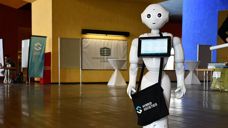 Ein Roboter hältein Tablet mit dem SFB混合社会的徽标。