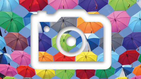 Icon einer Fotokamera vor einem Bild mit bunten Regenschirmen.