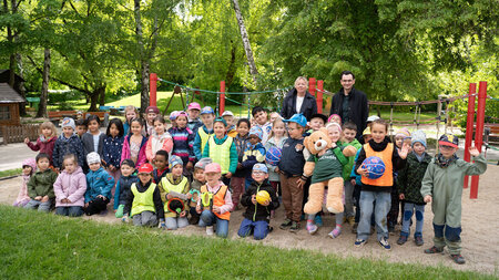 Kinder und Erwachsene stehen zusammen in einem Garten.