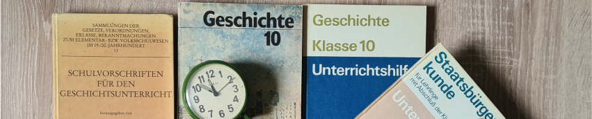 Alte Schulbücher aus der DDR mit einem Wecker, der fünf vor zwölf anzeigt