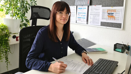 Eine Frau sitzt in einem Büro an einem Schreibtisch.