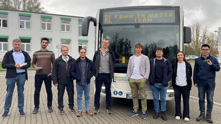 Mehrere Männer stehen nebeneinander vor einem Bus.