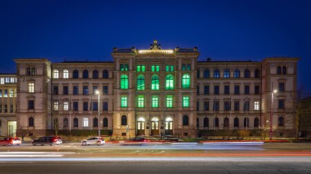 Mehrere Fenster eines Gebäudes erstrahlen grün.