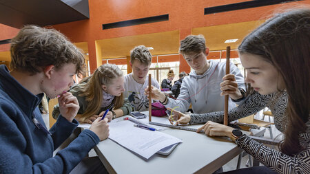 Fünf Schülerinnen und Schüler sitzen an einem Tisch und lösen Matheaufgaben.