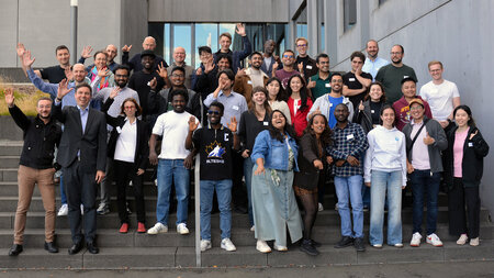 Mehrere Personen stehen auf einer Treppe. Viele von ihnen winken.