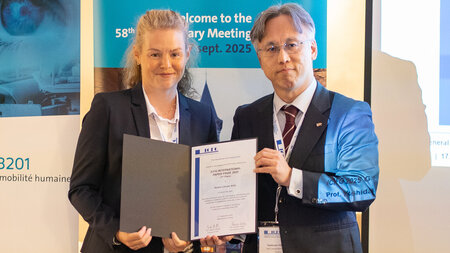 Ein Mann übergibt eine Urkunde an eine Frau.