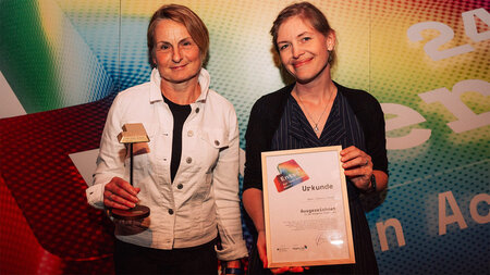 Two women hold a certificate in their hands