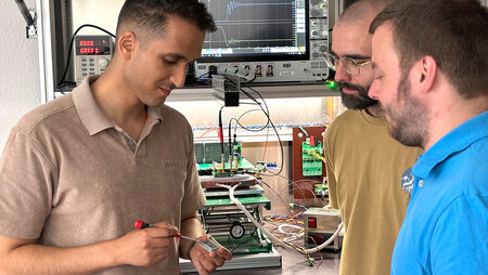Drei Männer arbeiten in einem Elektrolabor.