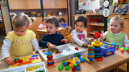 Kleine Kinder spielen an Tischen.