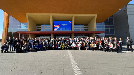 Many people stand in front of a building.