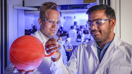 Two men hold a technical apparatus in their hands in the chemistry lab.