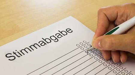 Eine Hand hält einen Stift auf einem Blatt Papier.