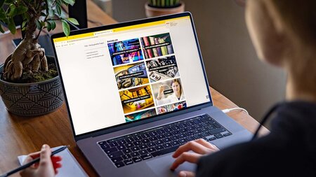 Eine Frau sitzt vor einem aufgeschlagenem Laptop