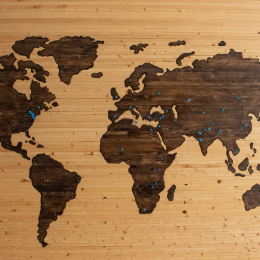 Weltkarte aus Holz mit mehreren blauen Heftzwecken