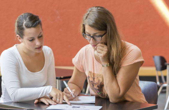 Zwei Studentinnen sitzen zusammen an einem Tisch